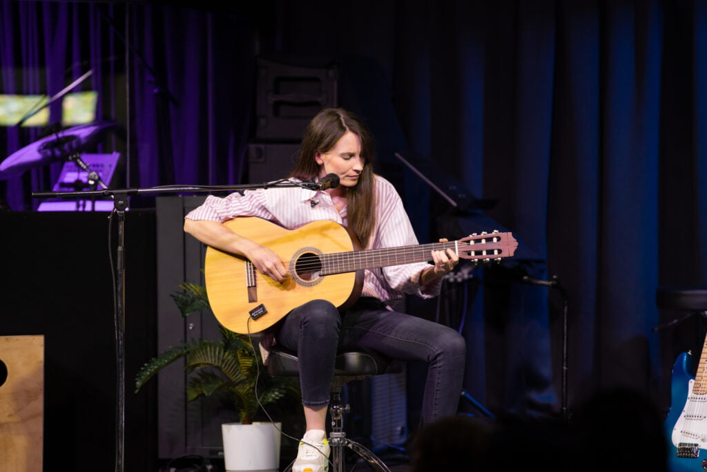 Alyce Chulu playing acoustic guitar